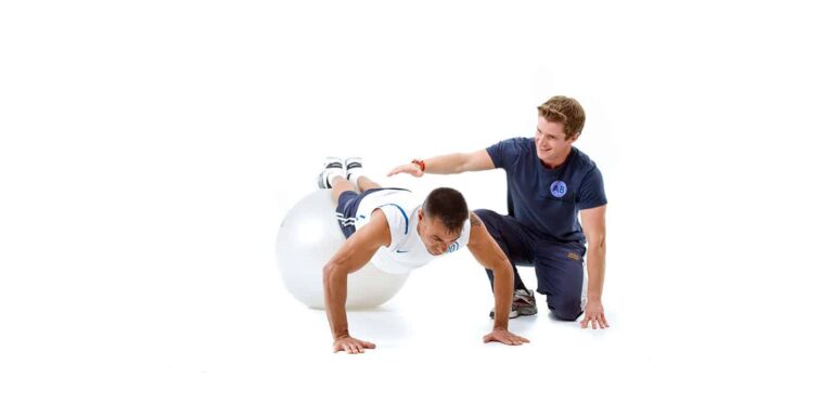 Alt text: Personal trainer helping client perform a core exercise with a stability ball at Anthony Bevington Fitness in Brighton & Hove.