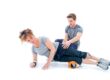 Personal trainer assisting woman with foam roller exercise for muscle recovery.