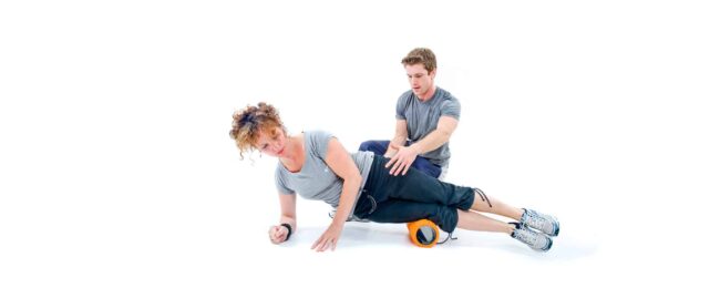 Anthony Bevington Fitness Training Session Personal trainer assisting woman with foam roller exercise for muscle recovery.
