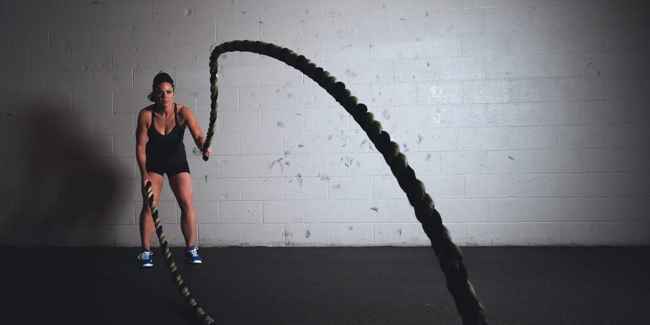 Female athlete performing intense battle ropes exercise at Anthony Bevington Fitness.