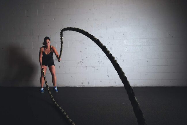 Female athlete performing intense battle ropes exercise at Anthony Bevington Fitness.