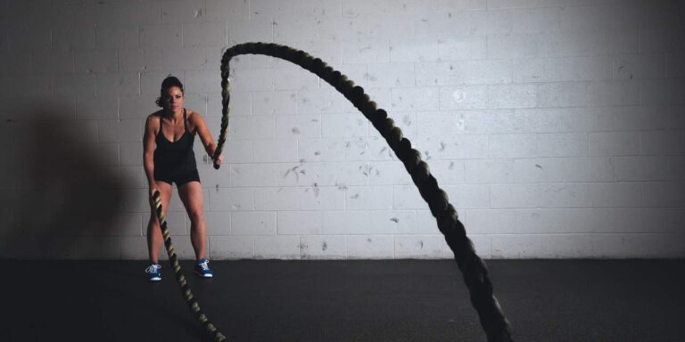Female athlete performing intense battle ropes exercise at Anthony Bevington Fitness.
